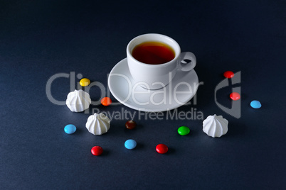 Cup tea and sweets on dark background