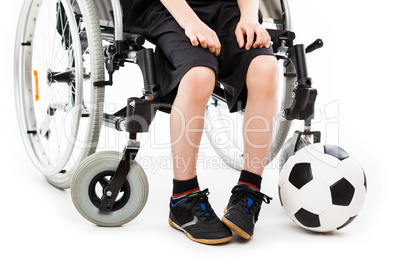 Disabled child boy sitting on wheelchair holding soccer ball