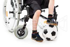 Disabled child boy sitting on wheelchair holding soccer ball