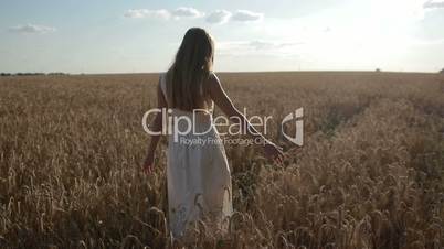 Happy woman walking on golden wheat field