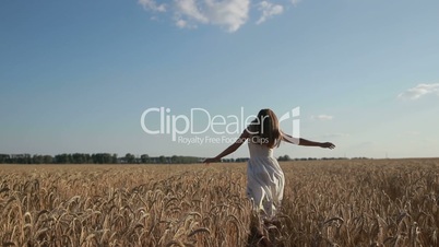 Woman in white dress running through wheat field