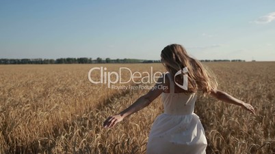 Carefree woman running through golden wheat field