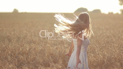 Excited woman spinning in wheat field at sunset