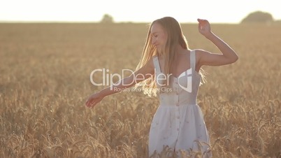 Lovely woman with flying hair in field at sunset