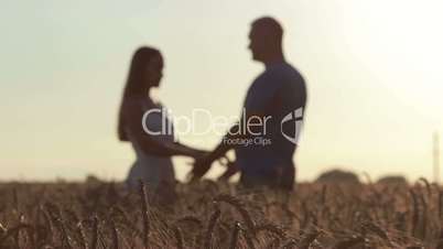 Couple holding hands in wheat field at sunset