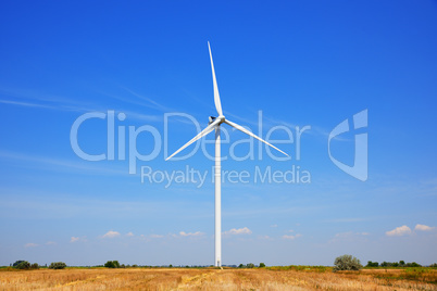 Windmill in a field against a blue sky