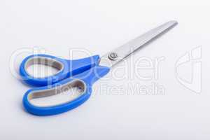 A closed pair of scissors with a blue grip