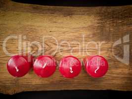 Four red candles on wood