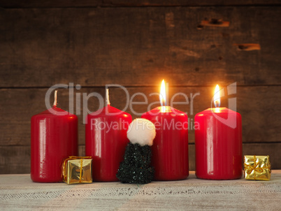 Four red candles on a wooden background