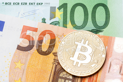 Golden bitcoin on hundred and fifty euro background.