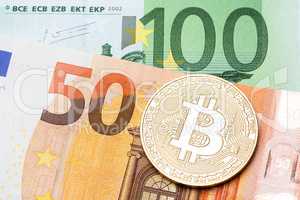 Golden bitcoin on hundred and fifty euro background.