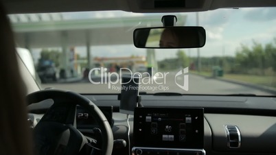 Female driver driving car on modern gas station