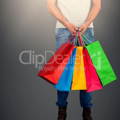 Composite image of low section of man carrying colorful shopping bag standing against white backgrou