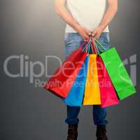 Composite image of low section of man carrying colorful shopping bag standing against white backgrou