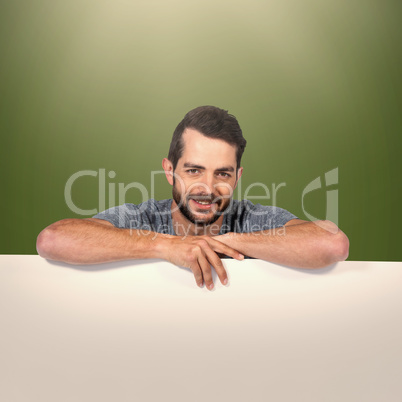 Composite image of portrait of smiling young man with cardboard against white background