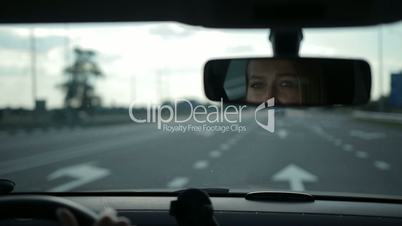 Reflection of lovely woman in car rear-view mirror