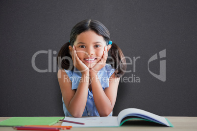 Composite image of portrait of girl doing homework at desk