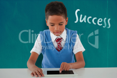 Composite image of schoolboy using digital tablet at table