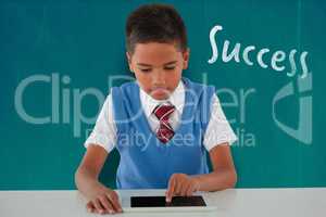 Composite image of schoolboy using digital tablet at table