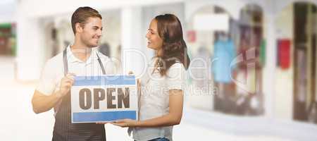 Composite image of happy coworker holding open sign