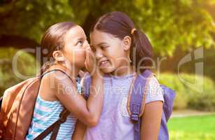 Composite image of student with backpack whispering in friend ear