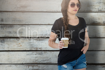 Composite image of female model holding disposable coffee cup against white background