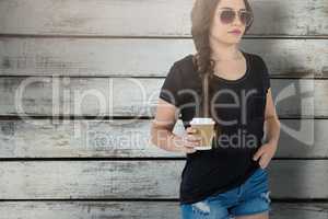 Composite image of female model holding disposable coffee cup against white background