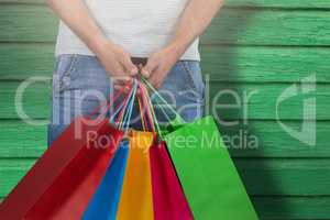 Composite image of midsection of man carrying colorful shopping bag against white background