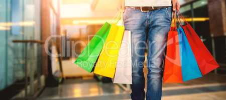 Composite image of low section of man carrying colorful shopping bag