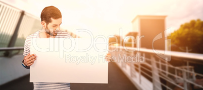 Composite image of man looking at blank cardboard