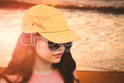 Composite image of beautiful female model wearing sunglasses and cap