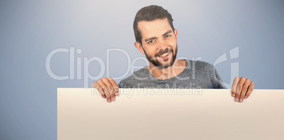 Composite image of portrait of smiling man holding cardboard