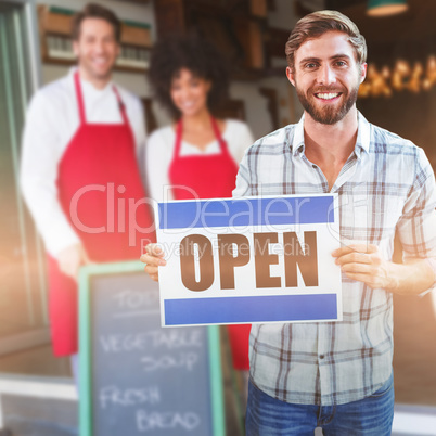 Composite image of portrait of male owner holding open sign