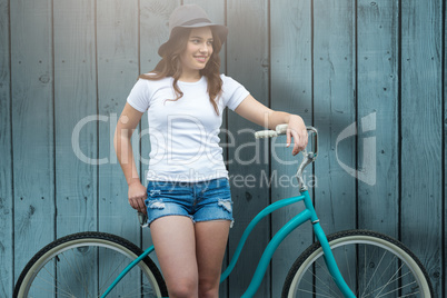 Composite image of smiling woman leaning on bicycle