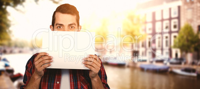 Composite image of portrait of man hiding face with cardboard