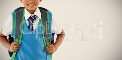 Schoolboy in school uniform with school bag on white background