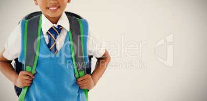 Schoolboy in school uniform with school bag on white background