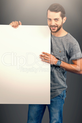 Composite image of portrait of smiling young man holding placard against white background