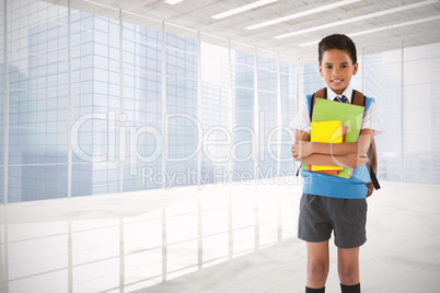 Composite image of portrait of schoolboy holding books over white background