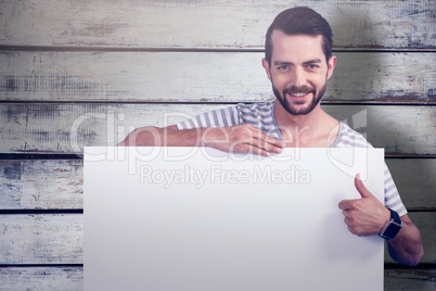 Composite image of portrait of man showing thumbs up while holding blank cardboard