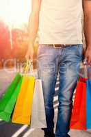 Composite image of low section of man carrying colorful shopping bag against white background