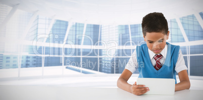 Composite image of schoolboy using tablet at table