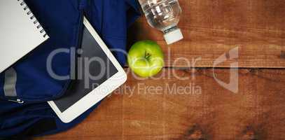Schoolbag with apple and digital tablet on table