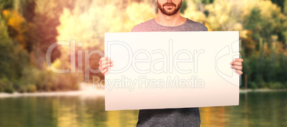 Composite image of midsection of young man holding cardboard