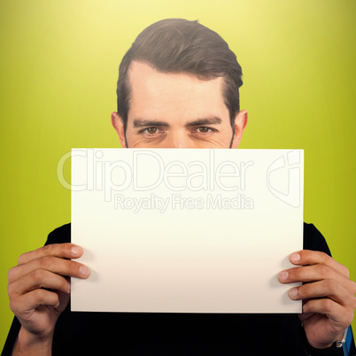 Composite image of portrait of young man hiding face with cardboard