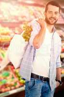 Composite image of portrait of young man carrying vegetables in shopping bag