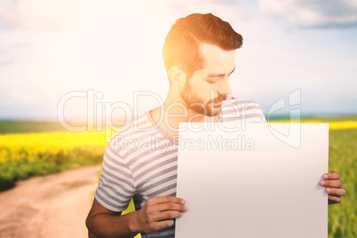 Composite image of young man looking at blank cardboard