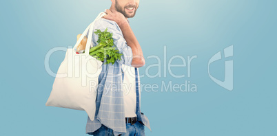 Composite image of portrait of man carrying vegetables in shopping bag