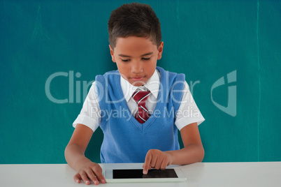 Composite image of schoolboy using digital tablet at table