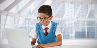 Composite image of schoolboy using laptop at table